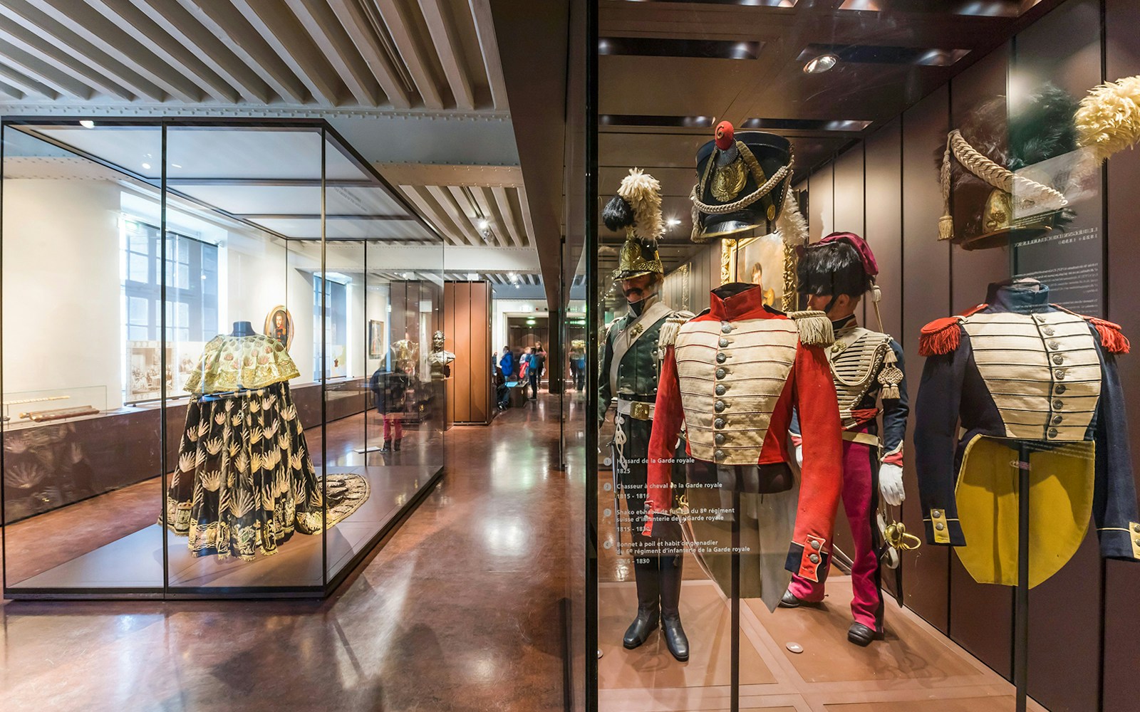 Armour suits and uniforms displayed at Army Museum, Paris with visitors exploring exhibits.