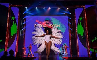 Performer on stage at RuPaul's Drag Race LIVE! Vegas show with feathered costume.