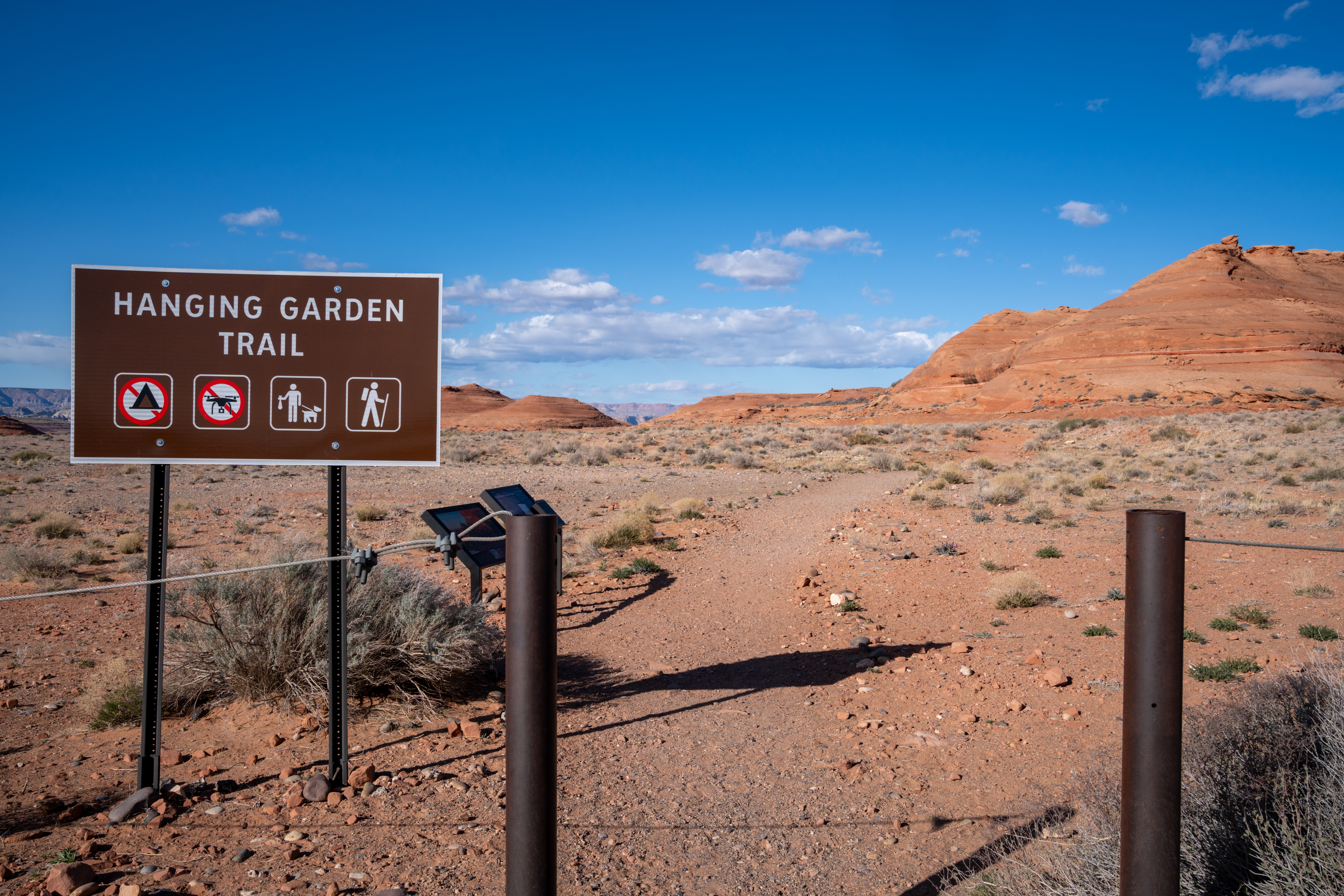 Hiking trail sign at the start of Hanging Garden Trail, Arizona, with desert landscape.