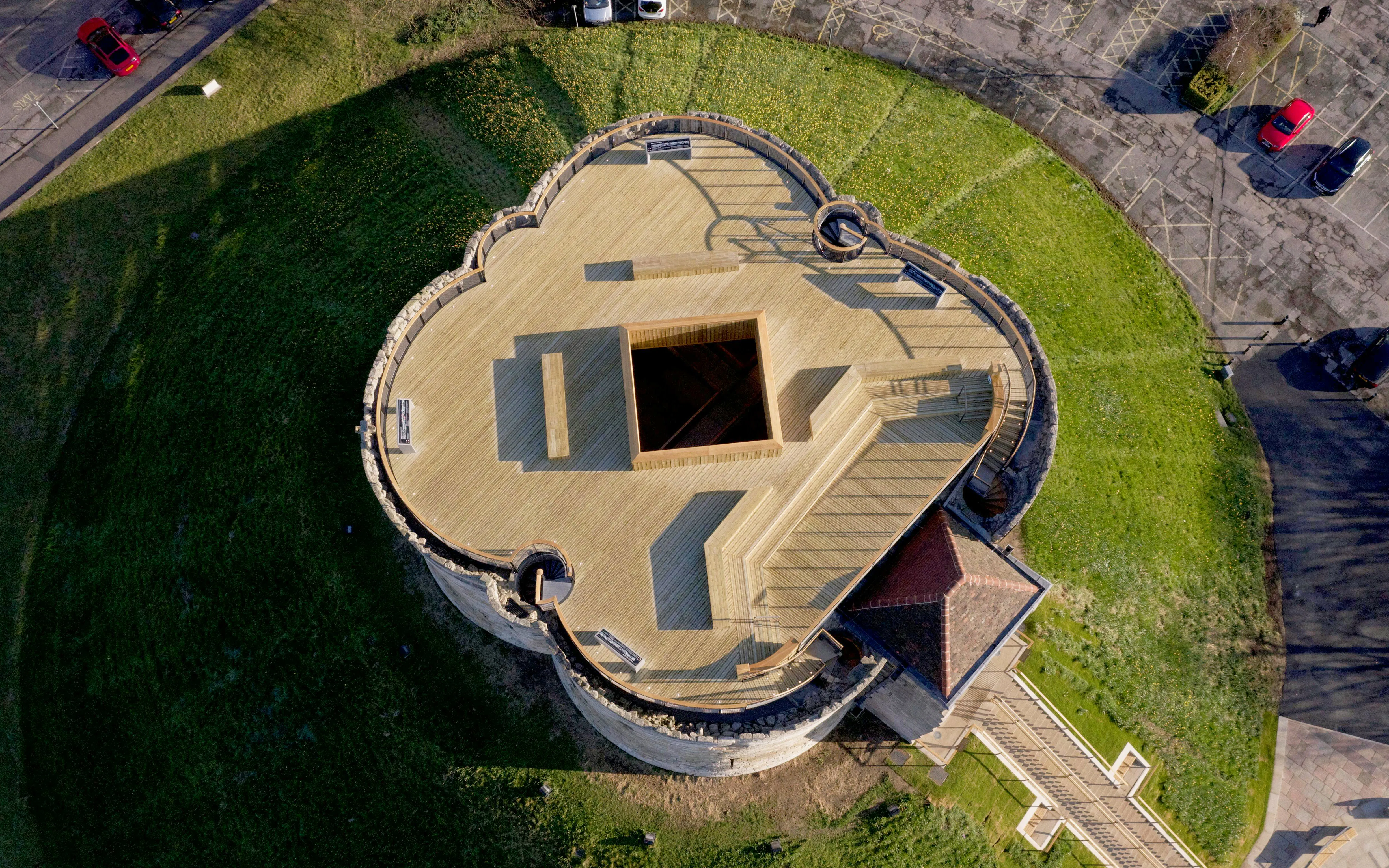 Aerial view of Clifford's Tower in York, showcasing its unique circular structure and surrounding green landscape.