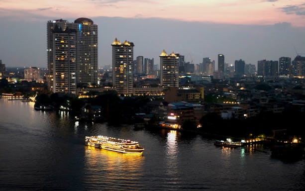 Chao Phraya Princess Cruise illuminated on Bangkok river at dusk with city skyline.