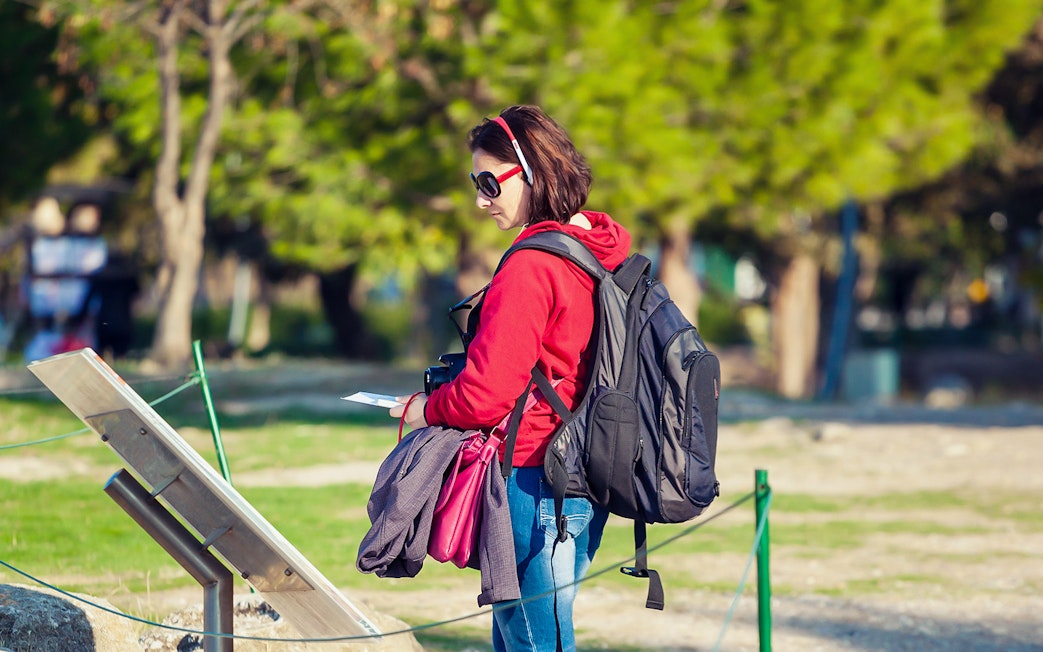 Tourist using audio guide in Pisa with Baptistery and Cathedral in background.