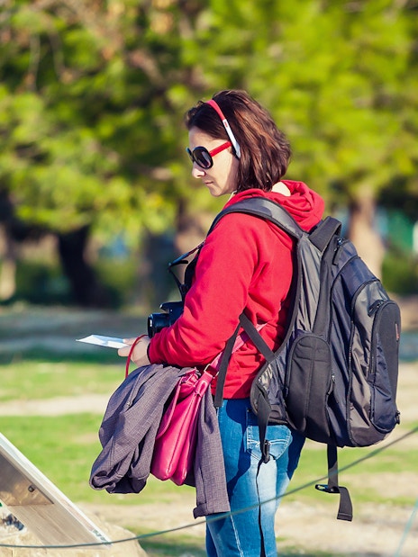 Tourist using audio guide in Pisa with Baptistery and Cathedral in background.