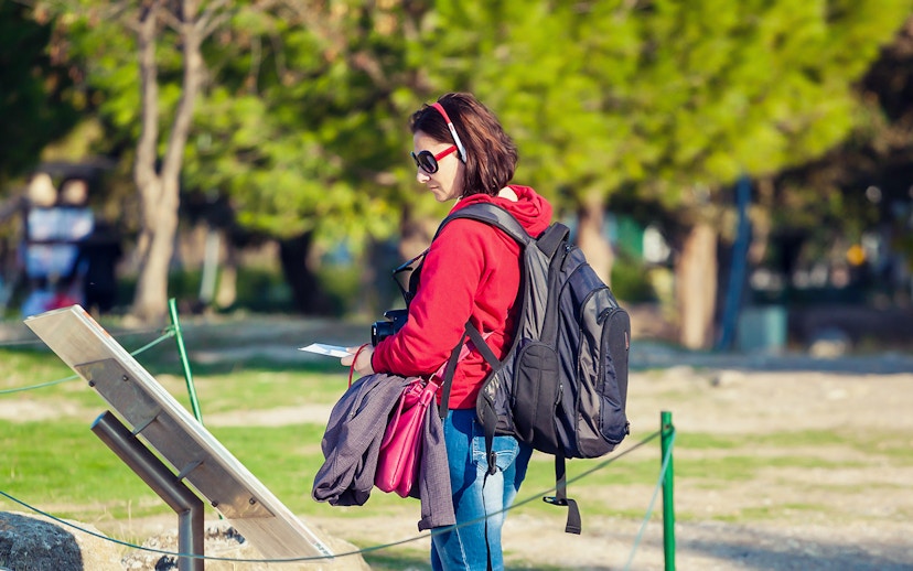Tourist using audio guide in Pisa with Baptistery and Cathedral in background.