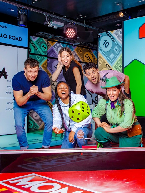 Guests enjoying the Monopoly Lifesized experience in London, rolling dice on a large game board.
