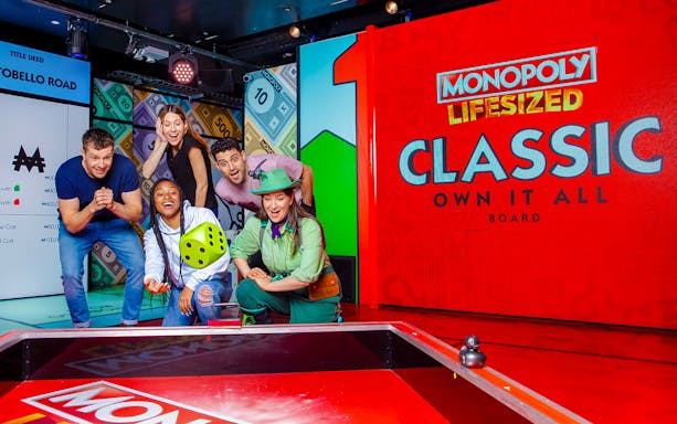 Guests playing a life-sized Monopoly game in London, interacting with oversized game pieces.