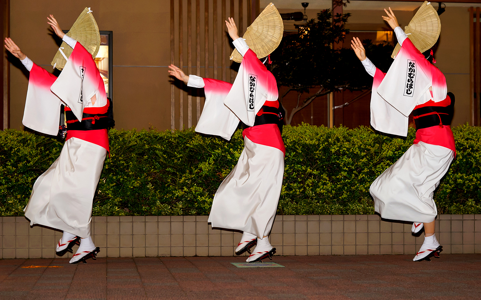 Dancers performing Awa Odori in traditional attire with straw hats.