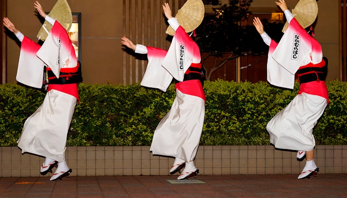Dancers performing Awa Odori in traditional attire with straw hats.