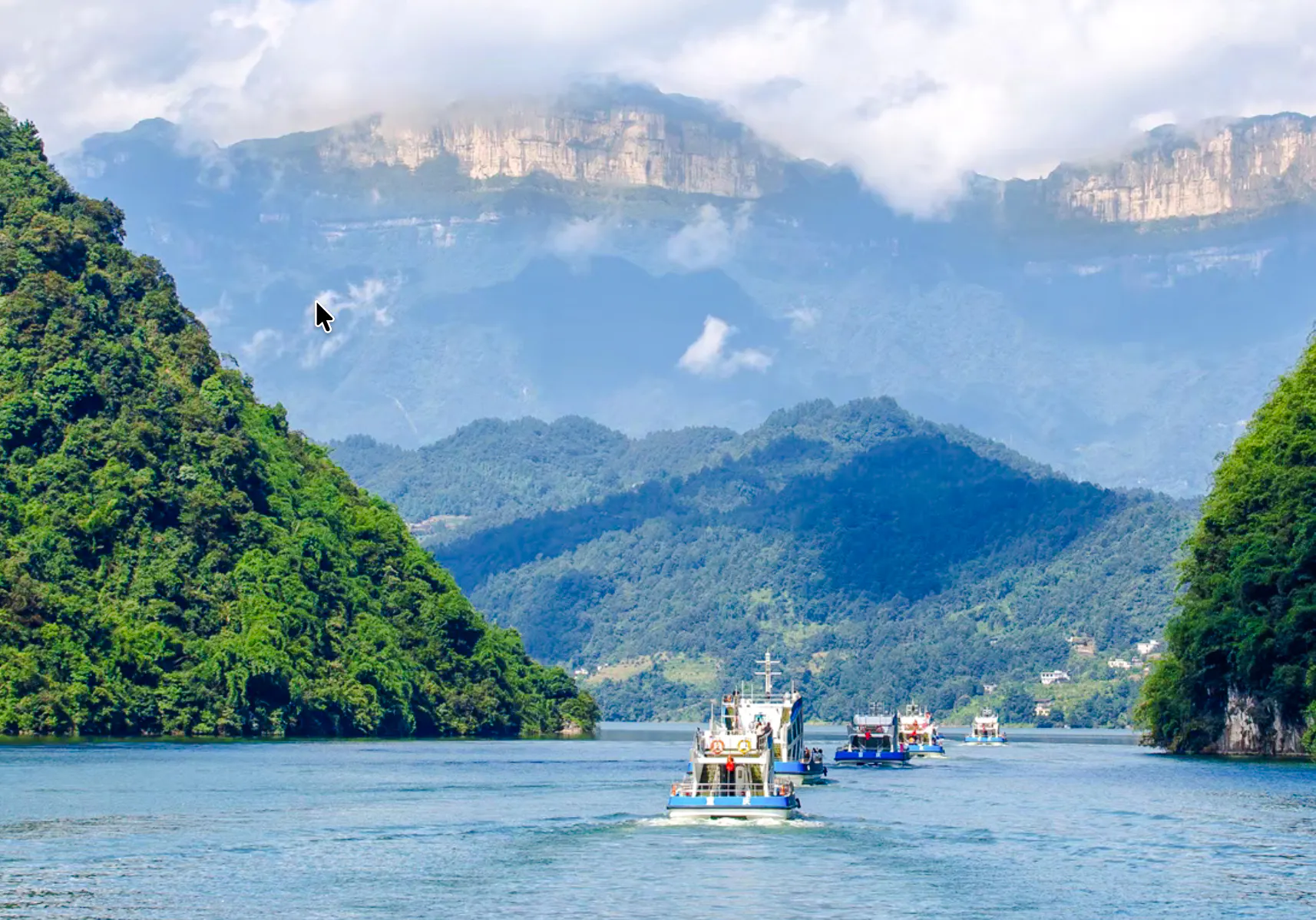 Boats cruising on Furong River with lush green mountains in Chongqing, China.