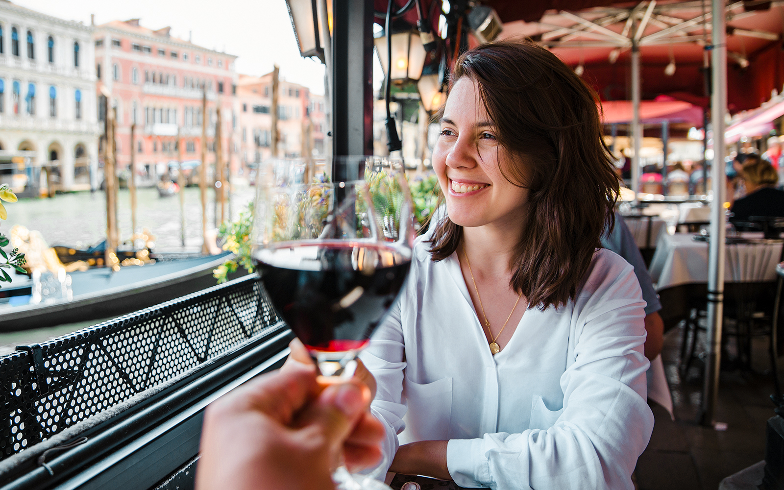 Couple enjoying wine at a Venice cafe with canal view.