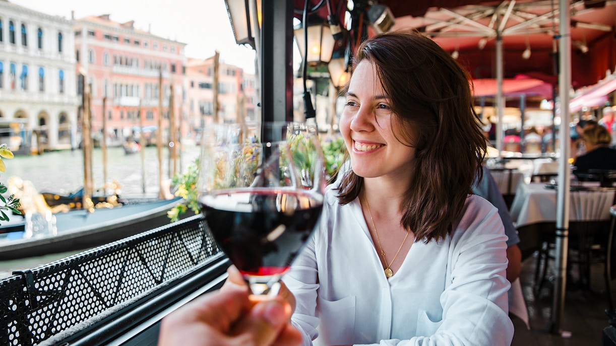 Couple enjoying wine at a Venice cafe with canal view.