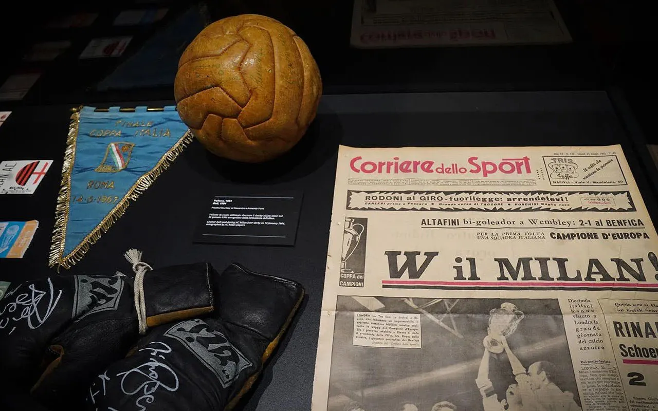 Vintage football memorabilia at Casa Milan Museum, Italy, featuring a leather ball, newspaper, and pennant.