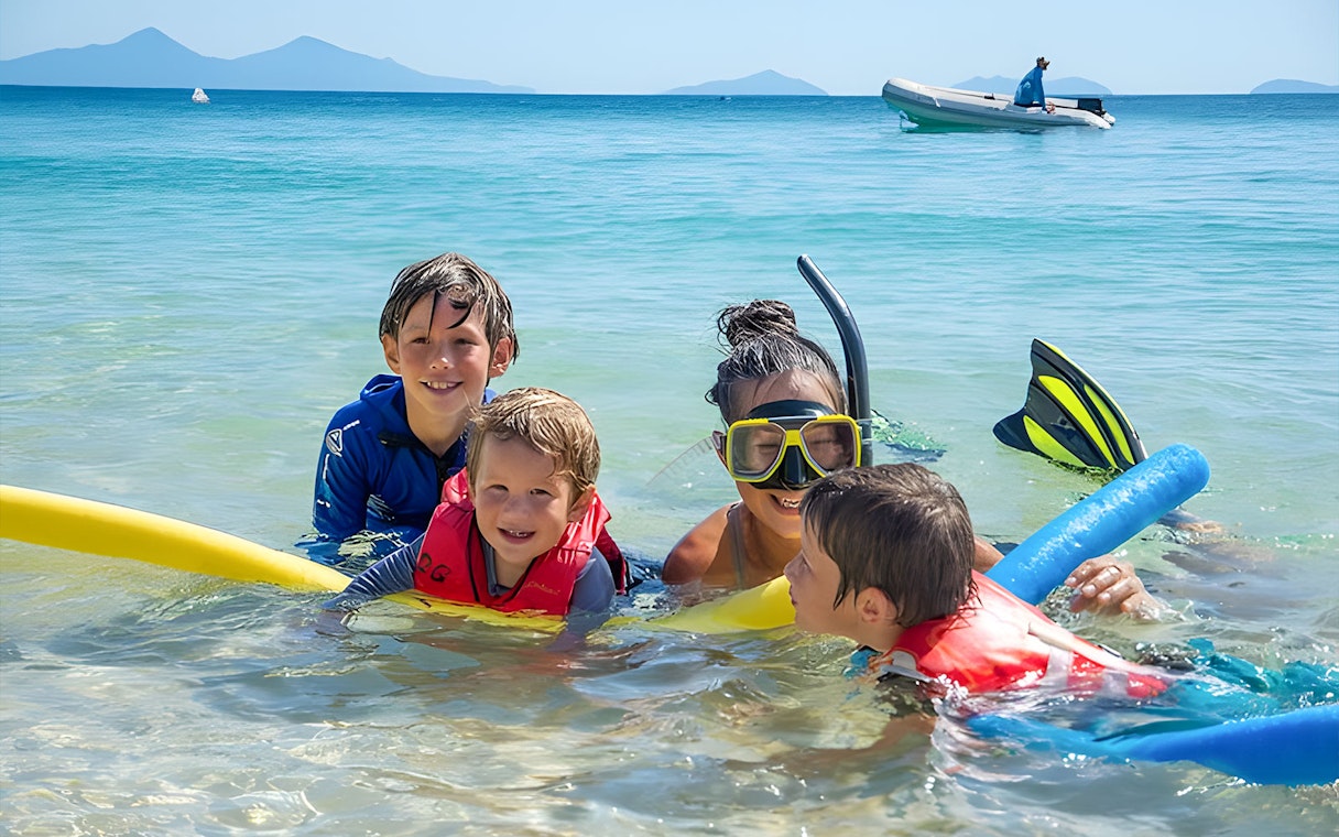Family snorkeling in clear waters at Frankland Islands, Australia.