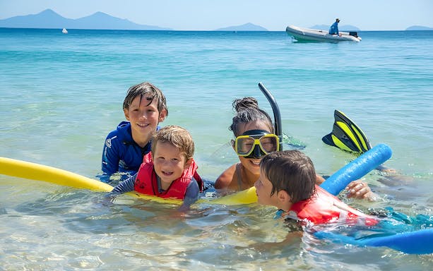 Family snorkeling in clear waters at Frankland Islands, Australia.