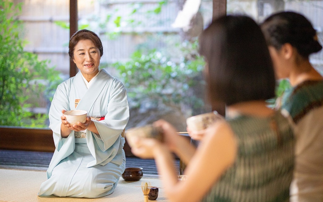 Tea ceremony in a traditional Machiya townhouse with a woman in a kimono serving tea.