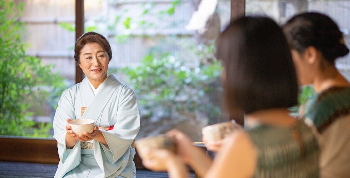 Tea ceremony in a traditional Machiya townhouse with a woman in a kimono serving tea.