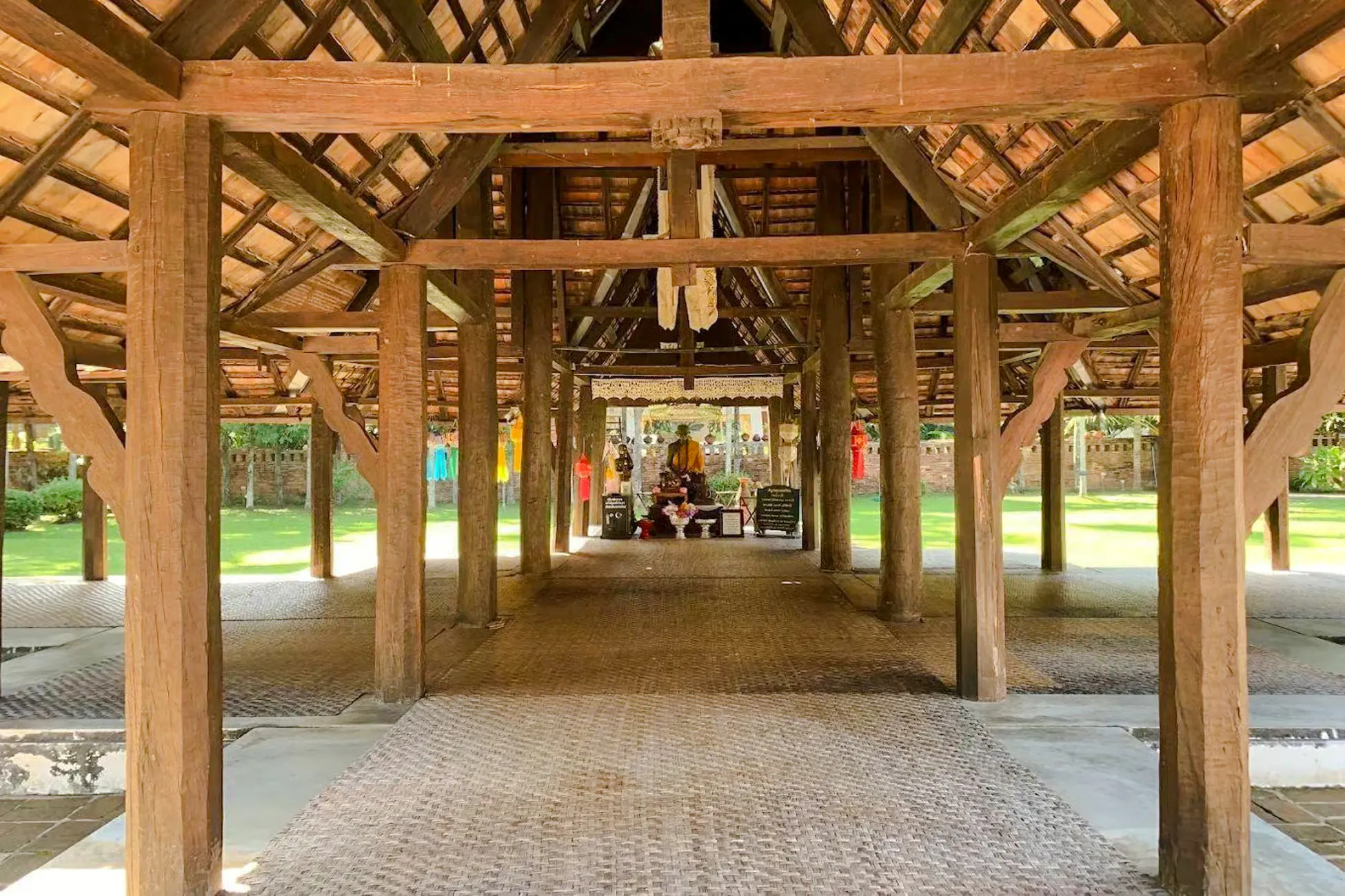 Traditional wooden pavilion with Buddha statue in Chiang Mai temple.