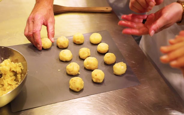 Hands shaping dough balls during a cooking class in Florence.
