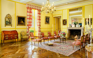 Chateau de Villandry sitting room with ornate chairs, fireplace, and chandelier.