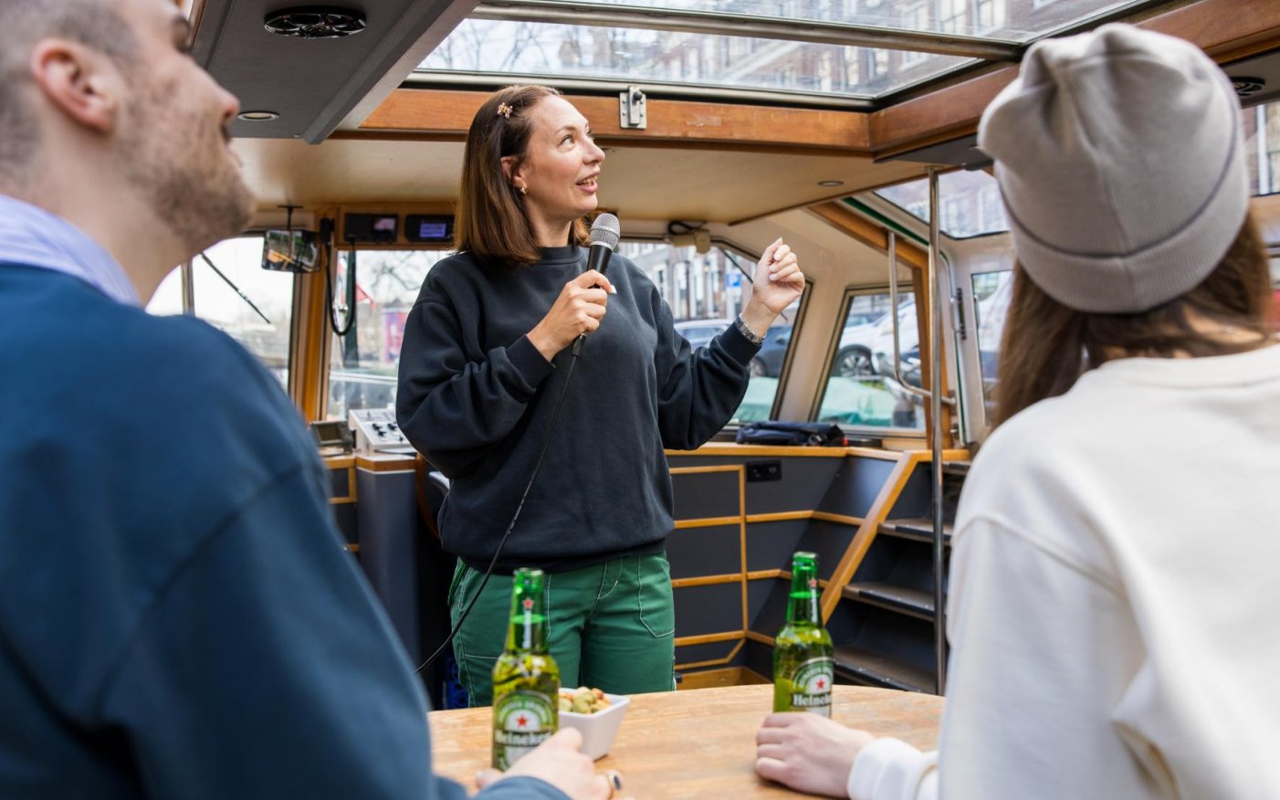 Live guide speaking to tourists on a Heineken Canal Cruise in Amsterdam.