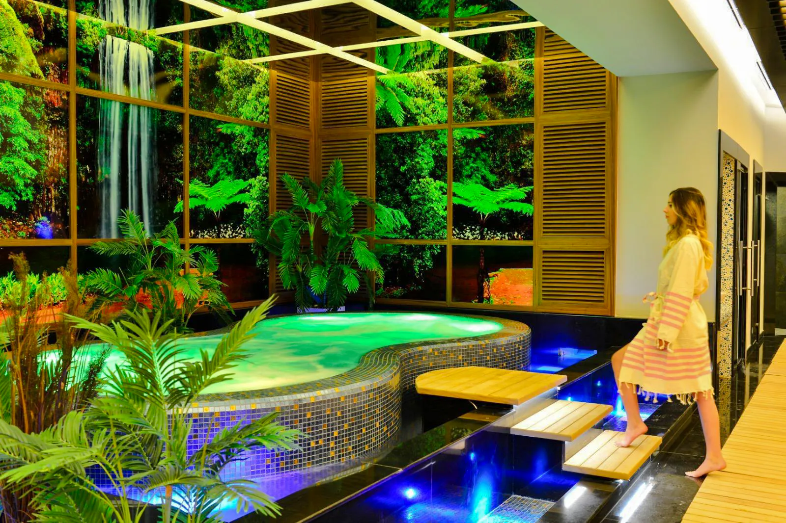 Woman entering a luxurious spa with a jacuzzi and tropical decor in Alanya.