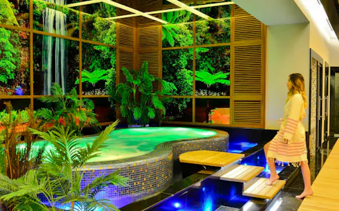 Woman entering a luxurious spa with a jacuzzi and tropical decor in Alanya.