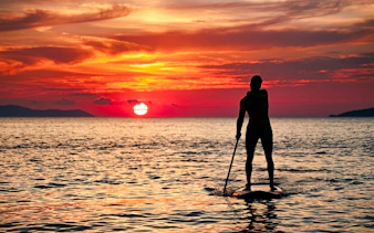 Person paddleboarding at sunrise in Rio de Janeiro.