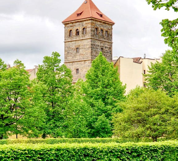 New Mill Water Tower in Prague surrounded by lush green trees.