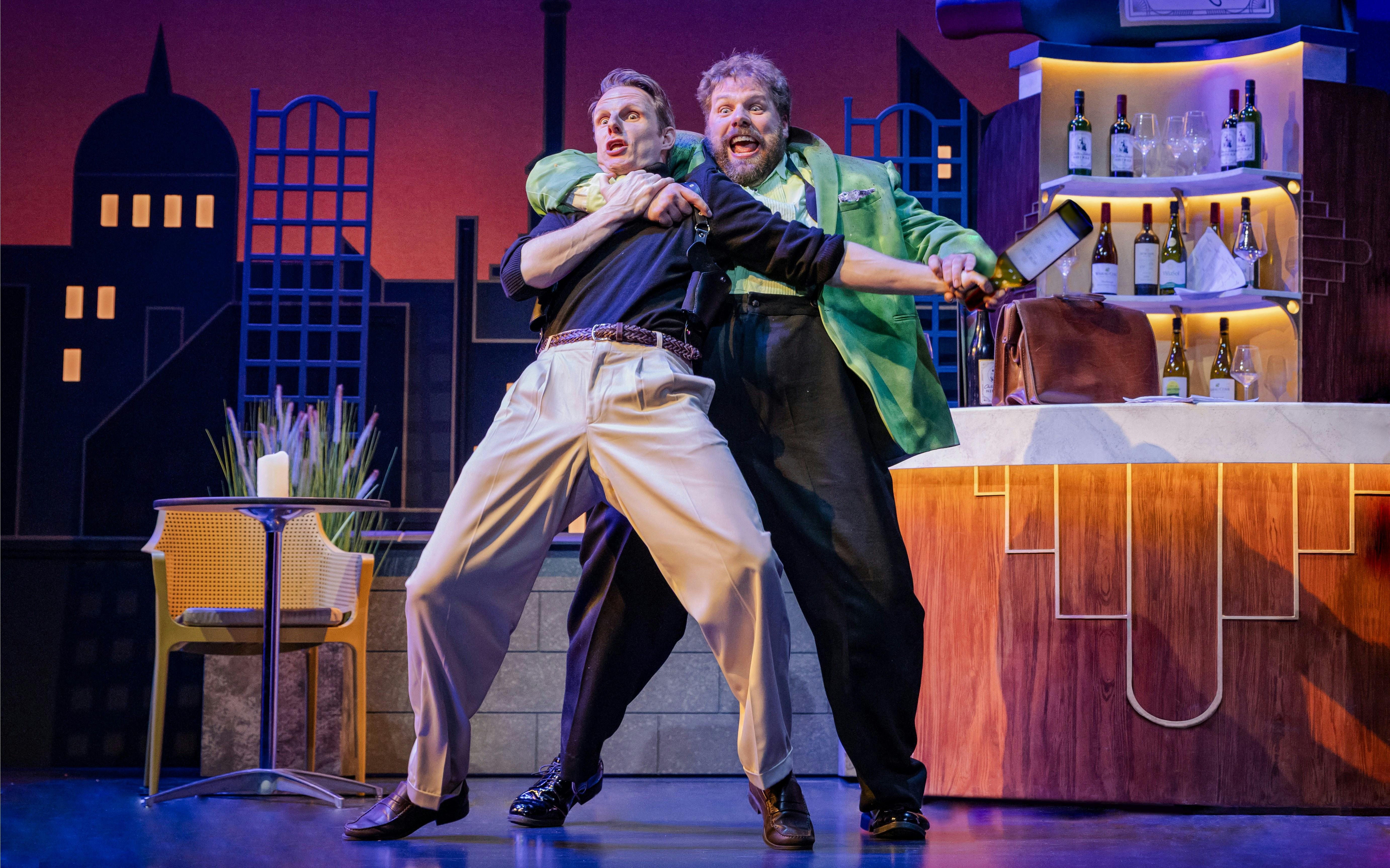 Actors in a comedic spy scene at a bar during "The Comedy About Spies" production.