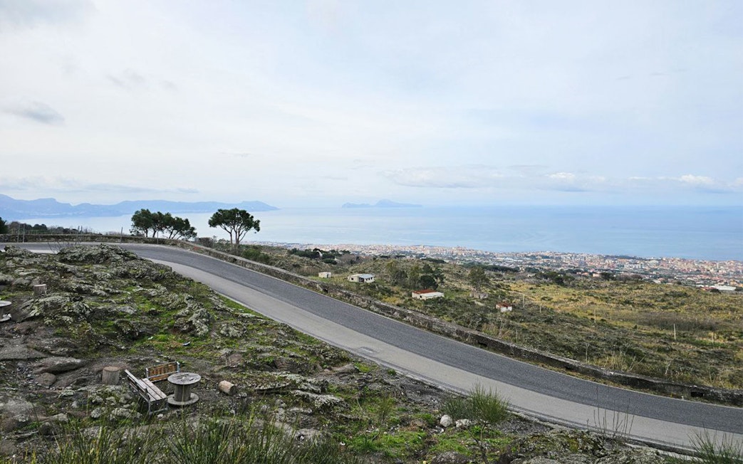 Winding road on Mount Vesuvius with view of Sorrento coastline and sea.