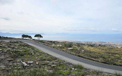 Winding road on Mount Vesuvius with view of Sorrento coastline and sea.