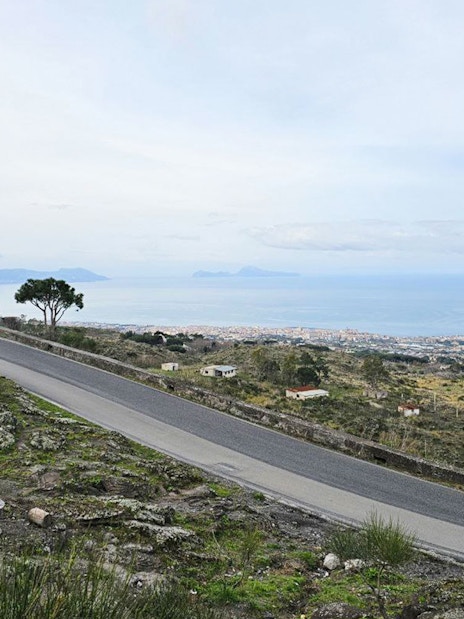 Winding road on Mount Vesuvius with view of Sorrento coastline and sea.