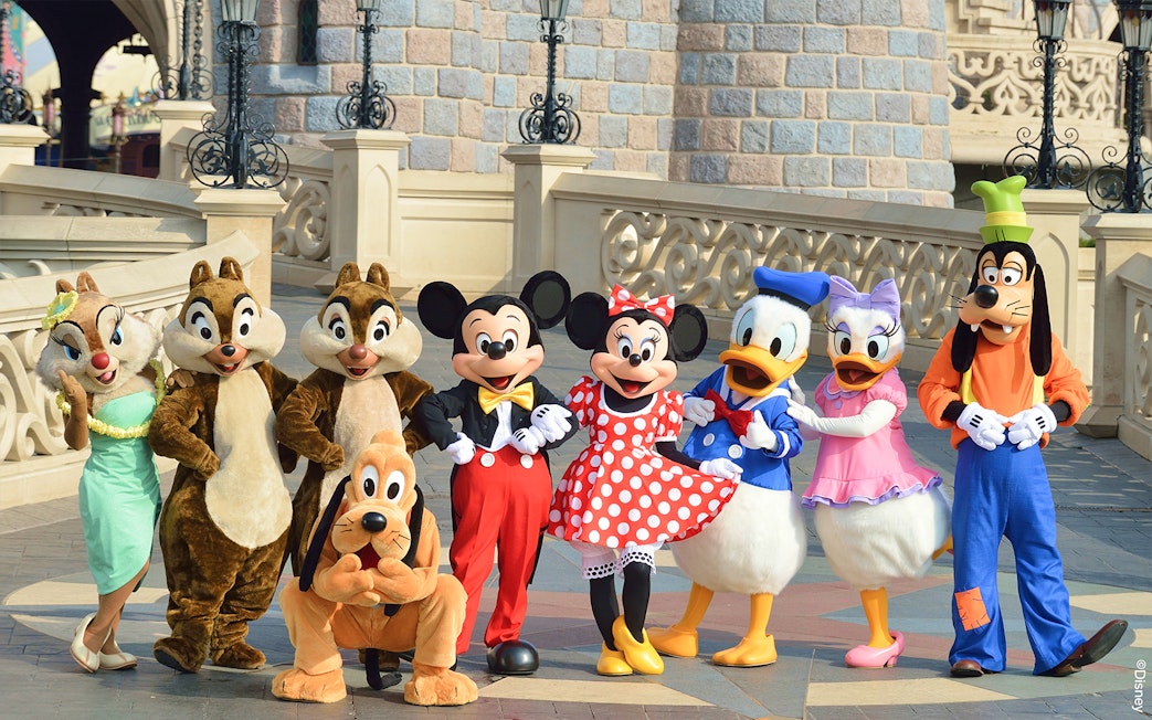 Disney characters posing in front of a castle at Disneyland Paris.