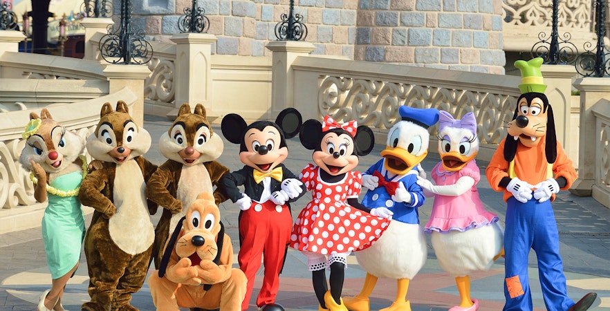 Disney characters posing in front of a castle at Disneyland Paris.