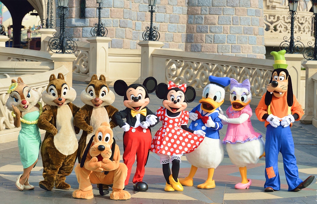 Disney characters posing in front of a castle at Disneyland Paris.