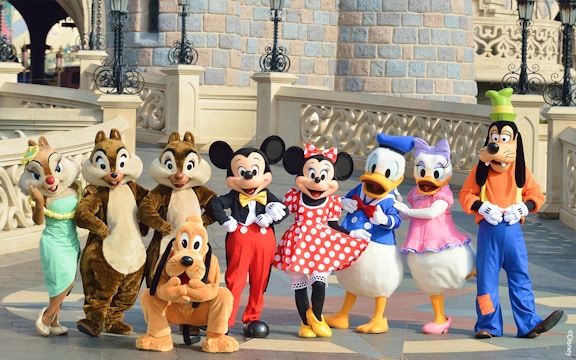 Disney characters posing in front of a castle at Disneyland Paris.