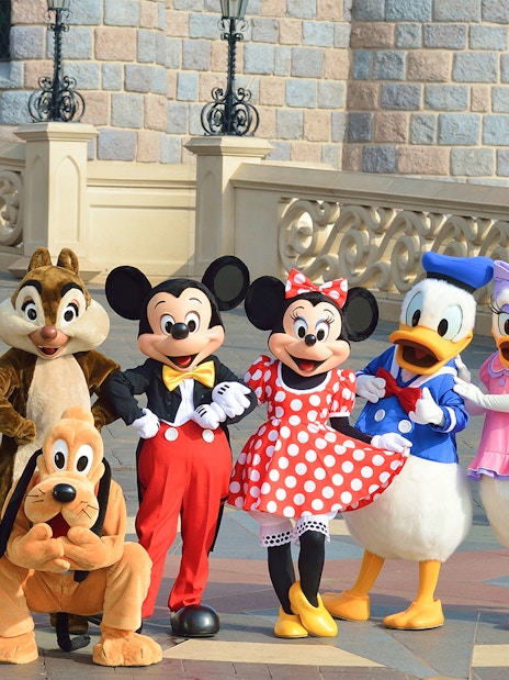 Disney characters posing in front of a castle at Disneyland Paris.