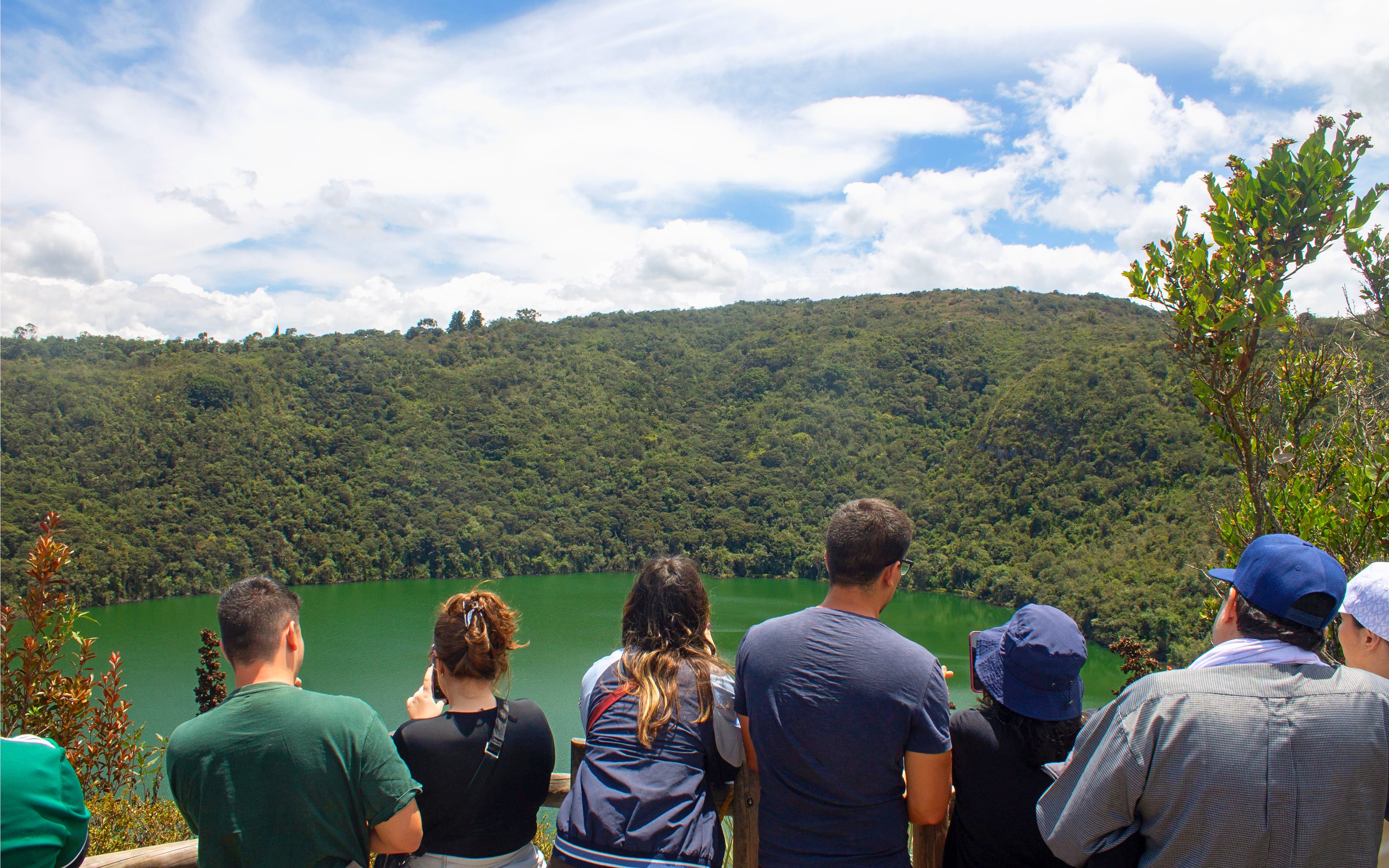 Visitors overlooking Guatavita Lake in Colombia surrounded by lush greenery.