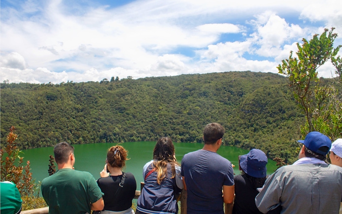 Visitors overlooking Guatavita Lake in Colombia surrounded by lush greenery.