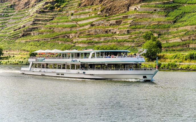 River cruise boat on the Moselle with vineyard terraces in the background near Koblenz.
