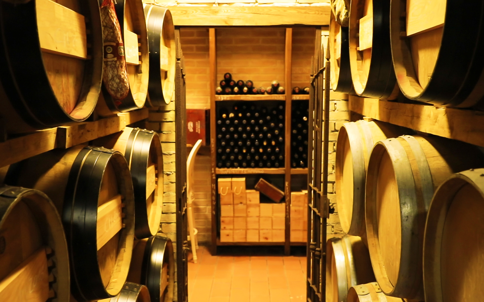Barrels and wine bottles in a Tuscan cellar, Chianti Classico tour.