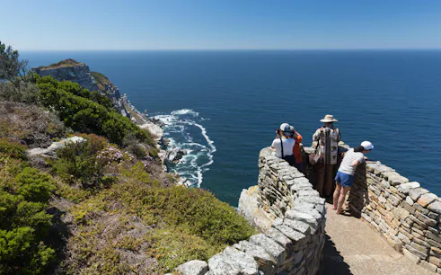 Visitors observing ocean views from a stone lookout at Cape Point, South Africa.