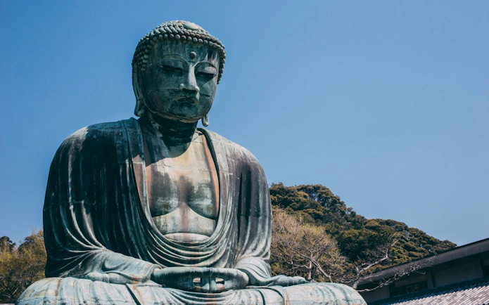 Kamakura Great Buddha statue with trees in the background, Japan.