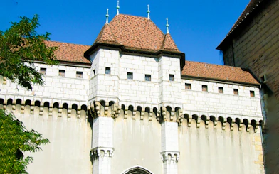Medieval castle facade in Annecy, France, with stone walls and red-tiled roof.