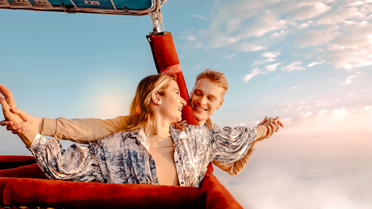 Hot air balloon ride over Dubai desert with couple enjoying the view.