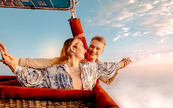 Hot air balloon ride over Dubai desert with couple enjoying the view.