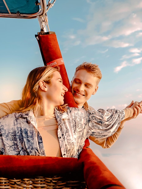 Hot air balloon ride over Dubai desert with couple enjoying the view.