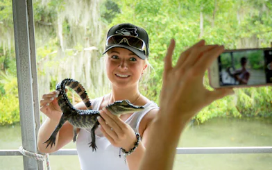Person holding a baby alligator during a New Orleans swamp tour.