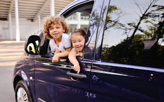 Children smiling from a car window during a Cinque Terre tour from Florence.