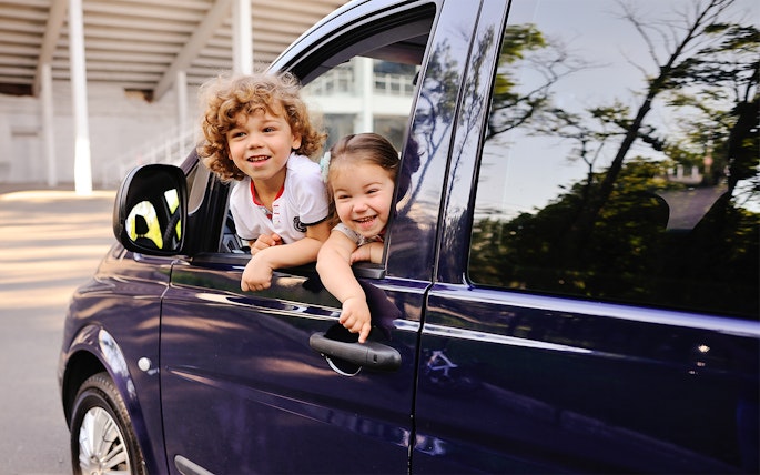 Children smiling from a car window during a Cinque Terre tour from Florence.